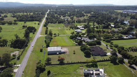 4k aerial video of a lush green rural suburb and a road with a few cars in australia
