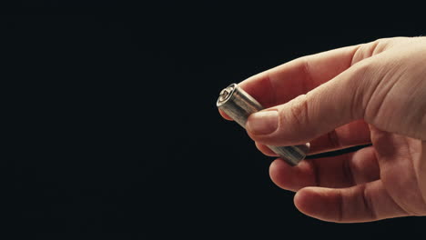 silver batteries aa and aaa in hands on black background close-up. double-a battery is a standard size single cell cylindrical dry battery. batteries are common in portable electronic devices. an aa battery is composed of a single electrochemical cell that may be either a primary battery or a rechar