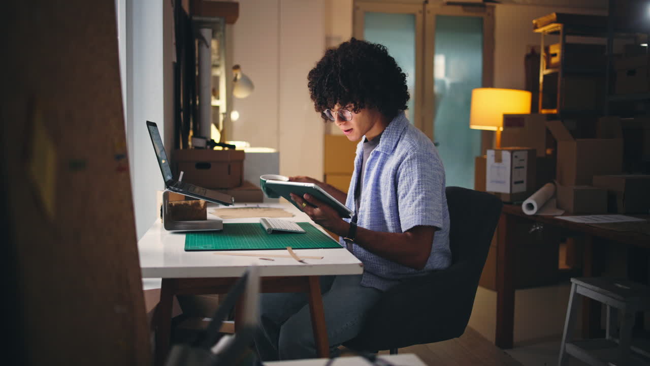 Giovane uomo che lavora su tablet e laptop in uno spazio di lavoro creativo