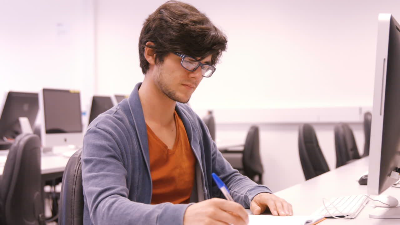 estudiante tomando notas y trabajando en la computadora