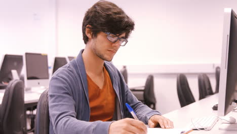 Student-taking-notes-and-working-on-computer