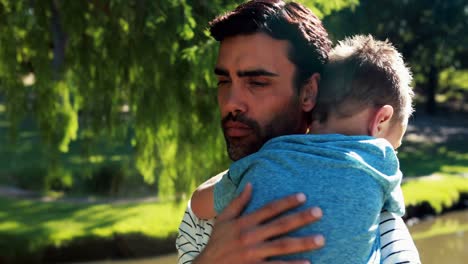 Father-holding-his-sleeping-son-in-park