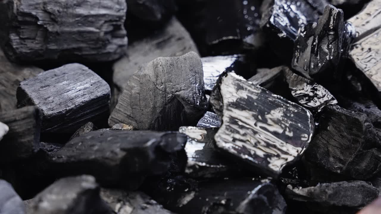 Flammable liquid splashes across coals preparing them for outdoor grilling