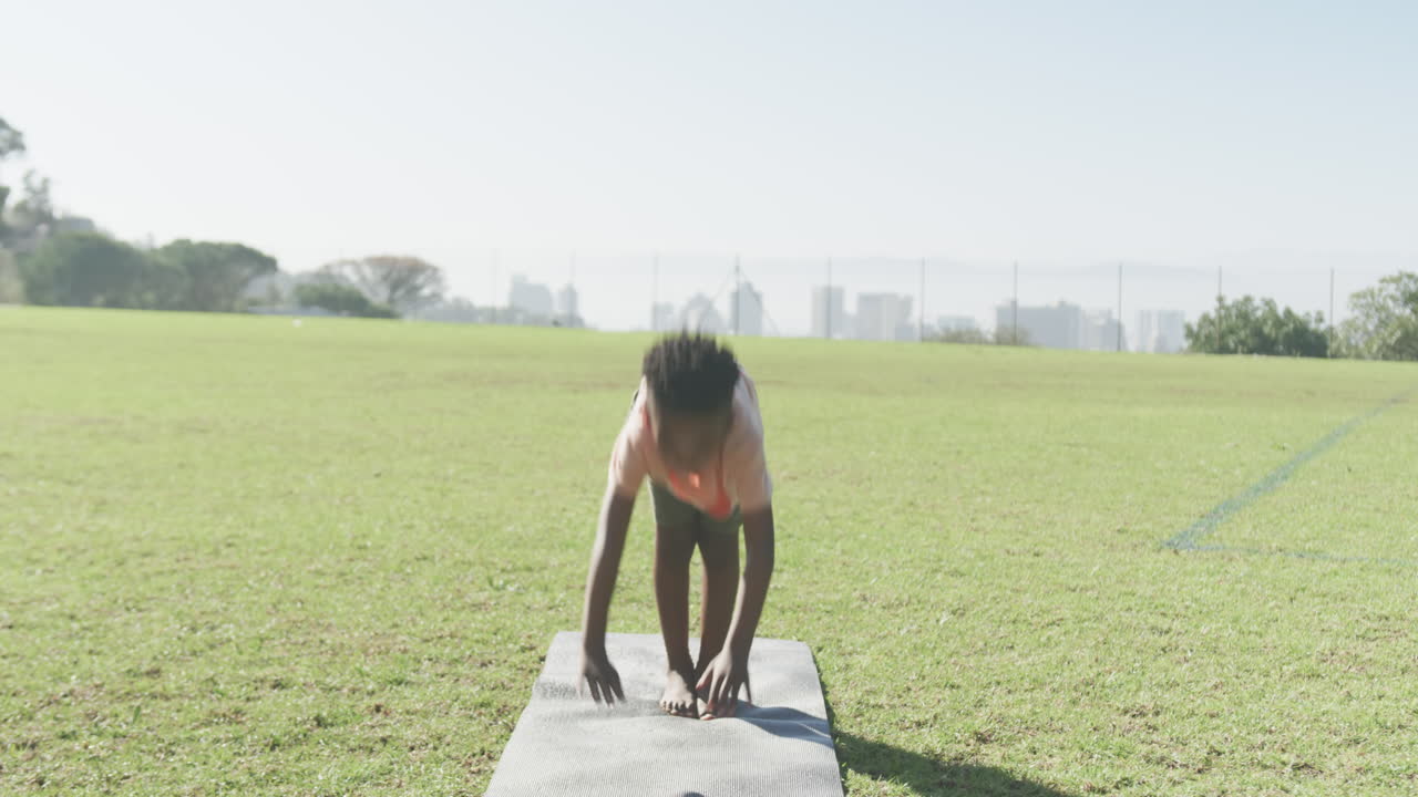 Practicing yoga, African American boy doing plank pose on mat in school field