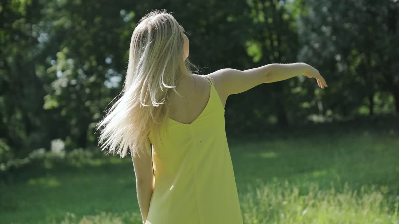 노란색 드레스를 입은 여자가 여름 공원에서 우아하게 춤을 춘다