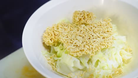 uncooked instant noodles with vegetable in white bowl , preparing thai style cheap street food