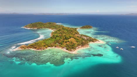 drone captures darocotan island off the coast of palawan, philippines, encircled by shallow coral reefs, white sand beaches, and lush tropical vegetation including cocos nucifera and coastal thickets