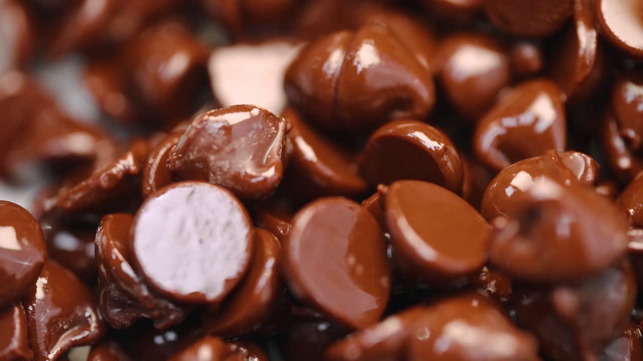 pila de chispas de chocolate semidulce oscuras derretidas calientes que brillan en macro de luz de cerca 4k de barrido de luz y panorámica a la derecha