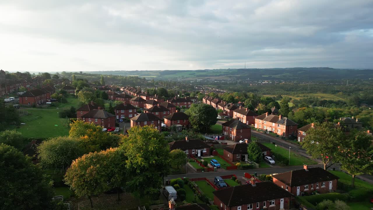 Yorkshire's urban life: Aerial view of a council-run housing estate with red brick houses, bathed in morning sunlight, and a lively atmosphere with people on the streets