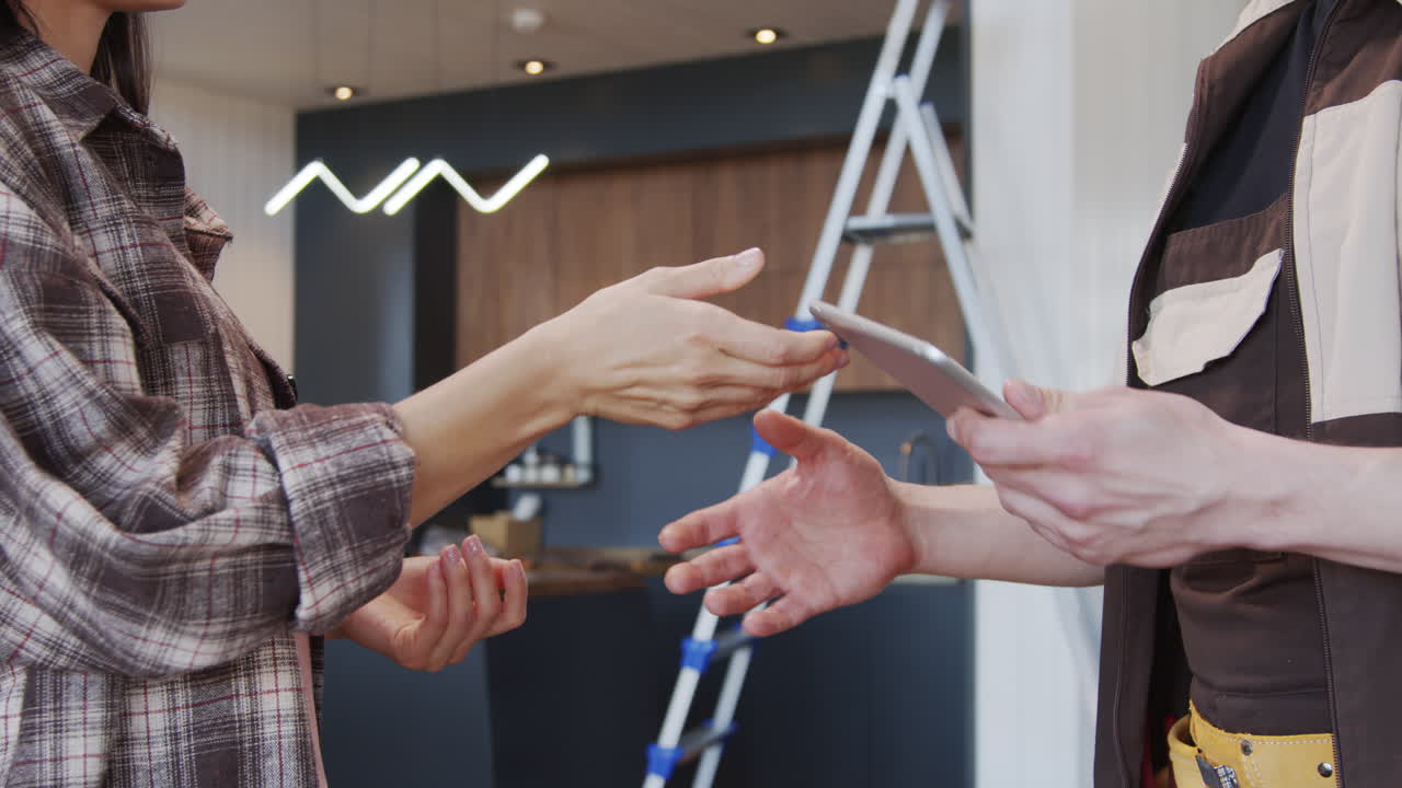 Woman Signing Receipt and Shaking Hands with Handyman