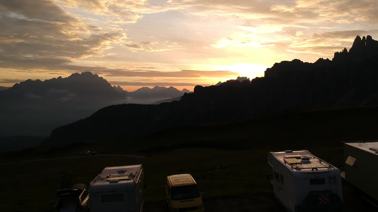 아름다운 풍경과 하늘을 배경으로 해가 뜰 때 돌로미티의 파소 지아우(passo giau)에 있는 놀라운 전망 지점에 주차된 캠핑카와 캠퍼밴 위의 공중 드론