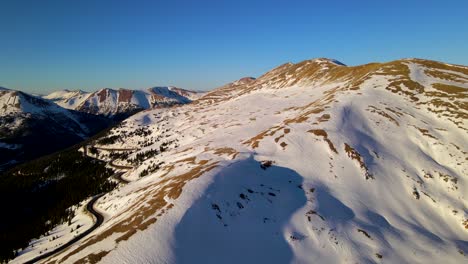 Aerial-panning-shot-of-beautiful-mountains-covered-in-snow-during-golden-hour