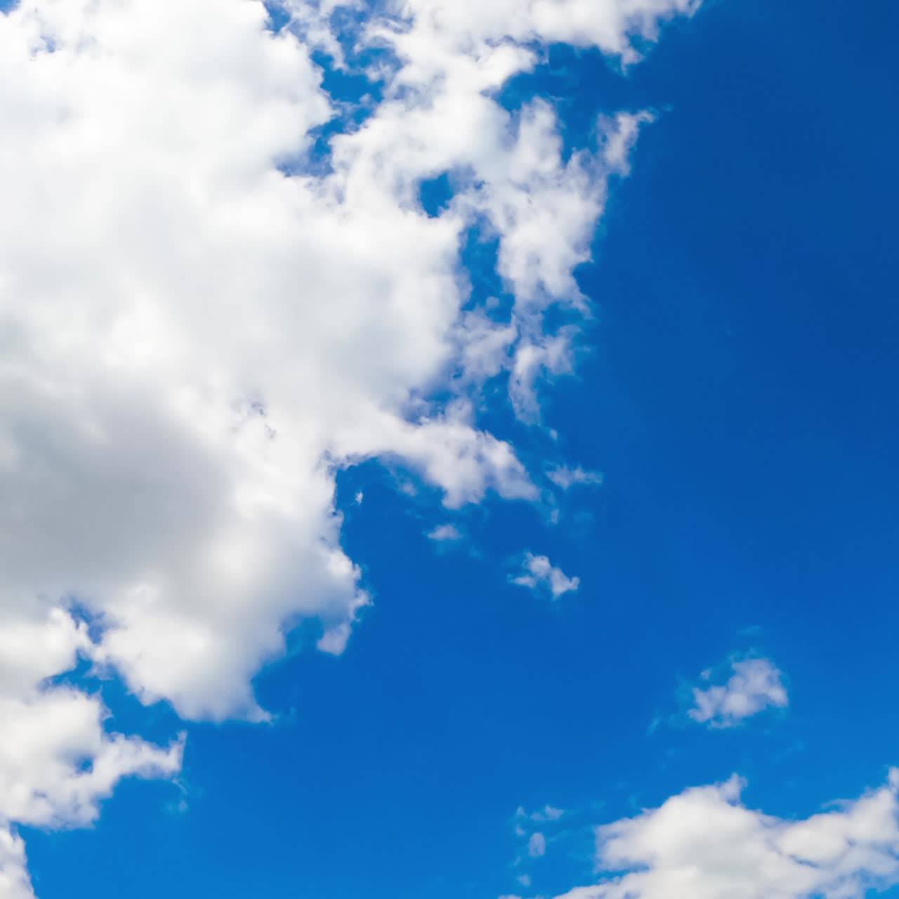 Cielo estivo azzurro e luminoso con nuvole bianche cumulate che si trasformano rapidamente. Angolazione dal basso. Timelapse