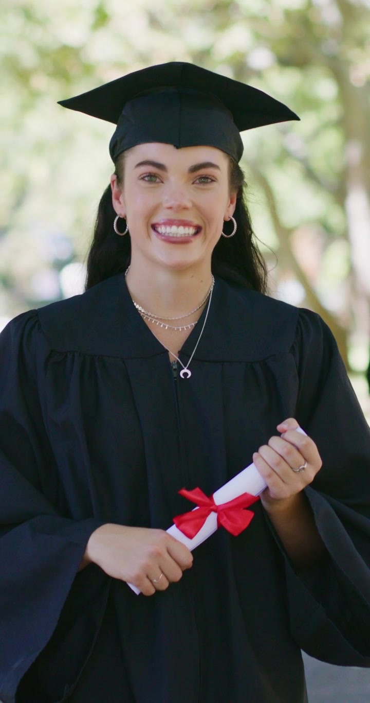 Giovane donna felice in toga di laurea che regge il diploma