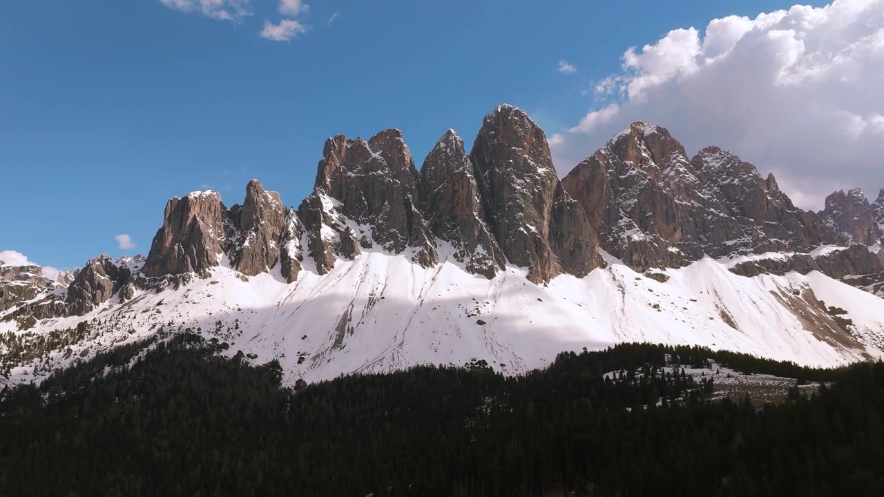 Den berømte Geisler Odle bjerggruppe med smeltende forårssne ved den klippefyldte base. Luftfoto af Dolomitterne, Italien.