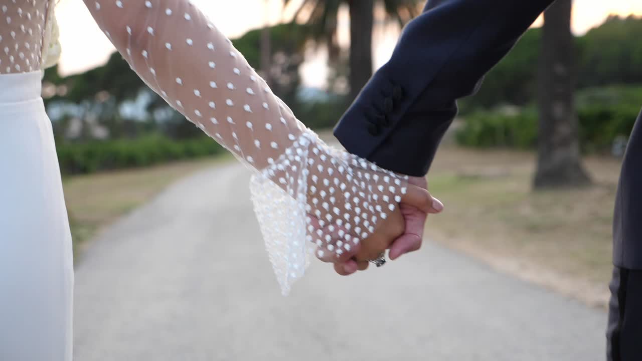 Married couple holding hands and walking in slow motion closeup on a pathway