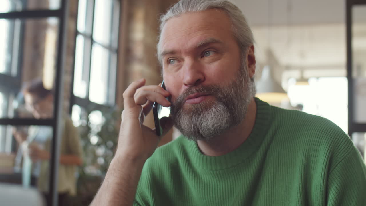 Older Man Talking on Phone in Cafe