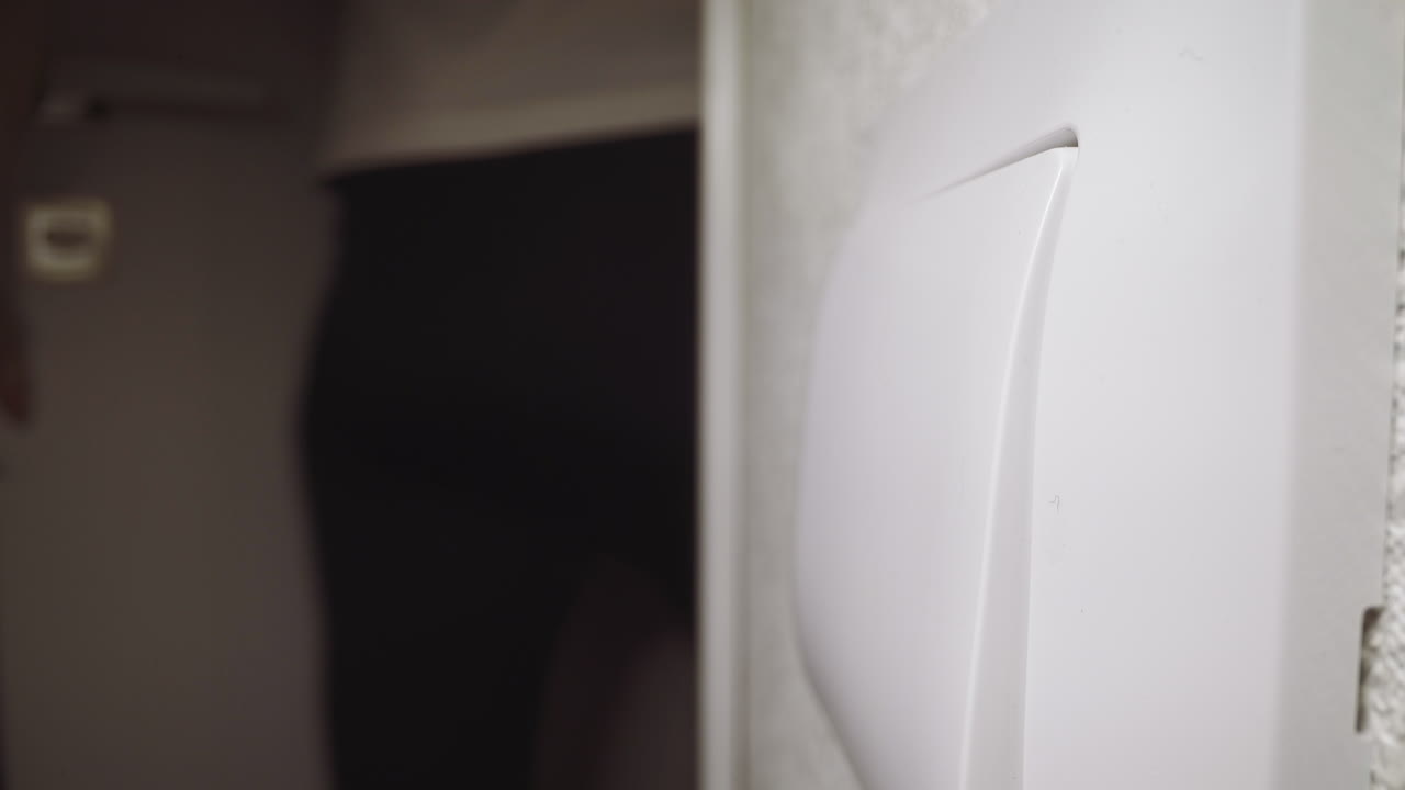 여자 는 방 에 들어오는 빛 을 켜기 위해 스위치 키 를 누른다