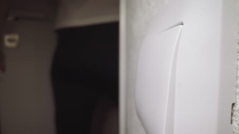 la mujer presiona la tecla del interruptor para encender la luz que entra en la habitación