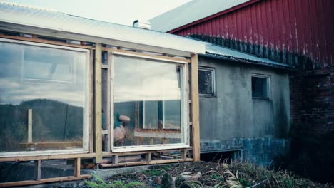 man installing wood planks on glass window wall frame of a house