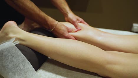 a massage therapist is applying pressure to the woman's leg while massaging it - close up