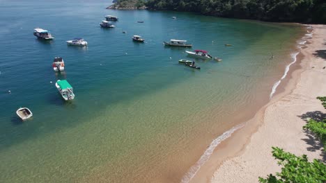 discesa aerea verso una piccola spiaggia oceanica brasiliana fiancheggiata da piccole barche