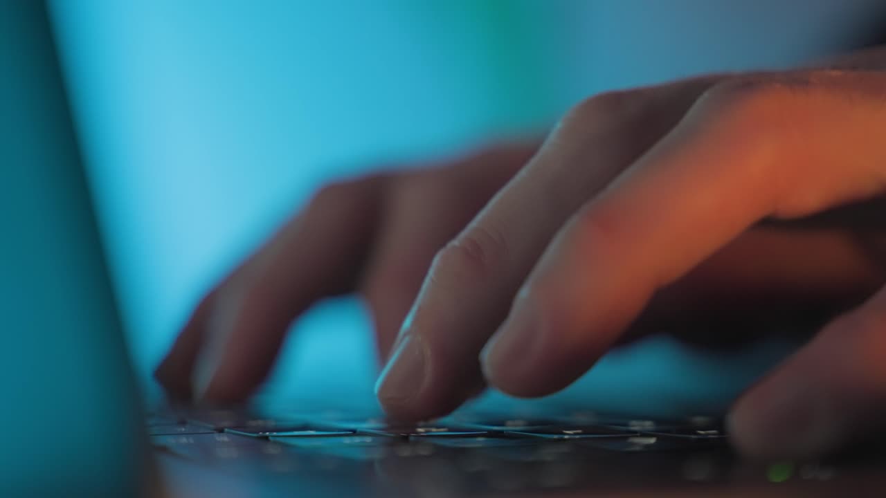 Hænder, der skriver på et laptop-tastatur i blåt lys. Hacking, it-kriminalitet, malware-angreb, databrud og cybersikkerhedstrussel-koncept. Arbejde på sene nattevagter. Skriver på kontoret. Hacker på arbejde