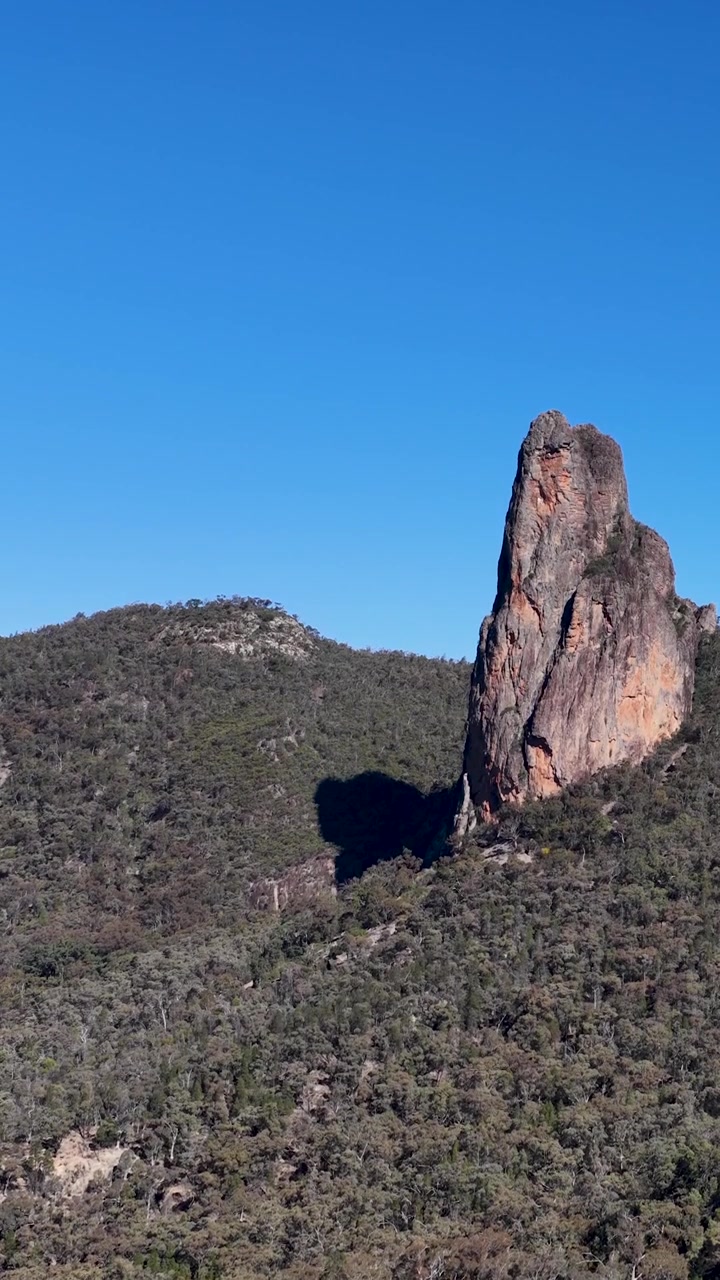 Inquadratura ampia statica del neck vulcanico The Breadknife sotto un cielo azzurro e limpido in Australia