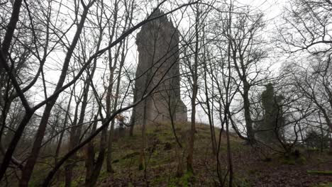 tilting shot of the national wallace monument from the woodland with fog surrounding