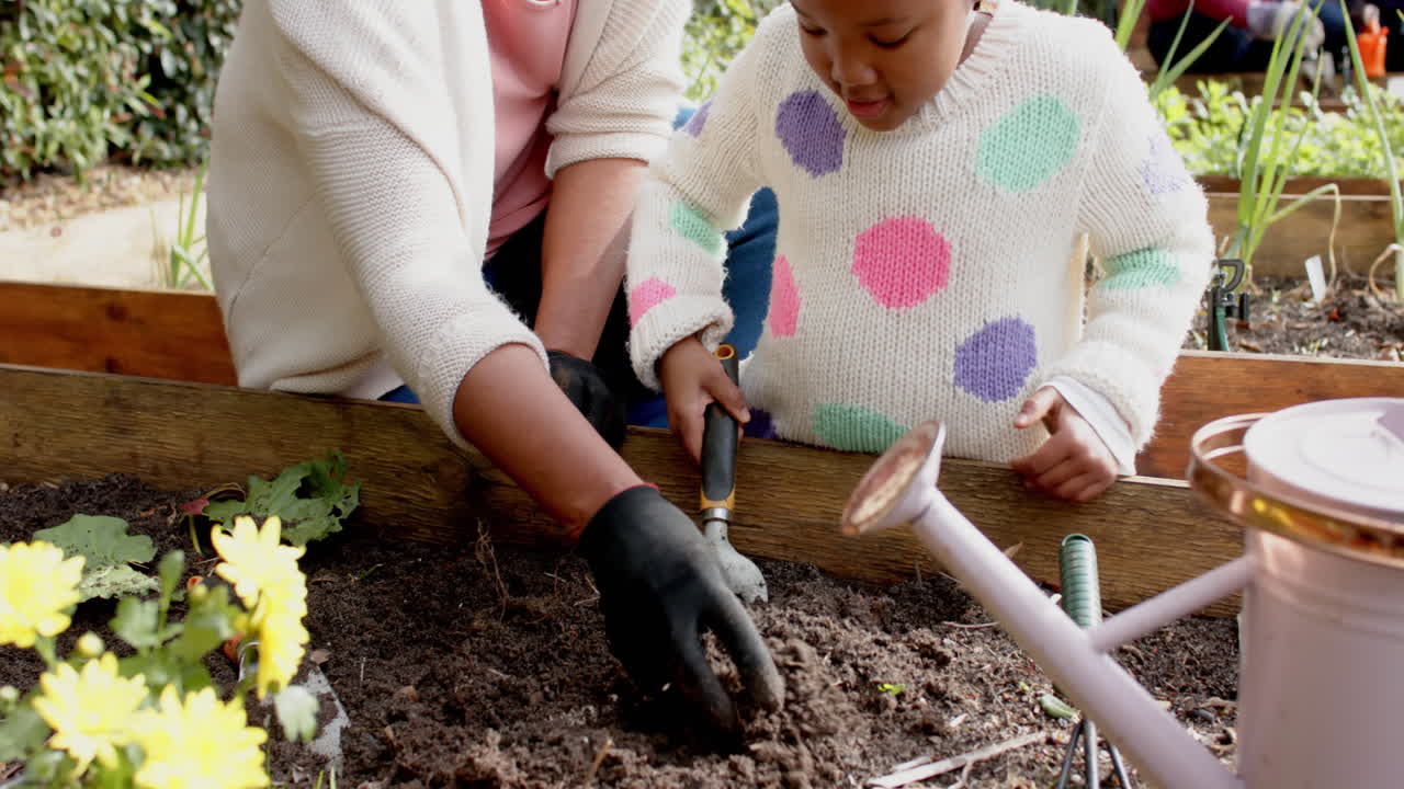feliz abuela afroamericana y nieta jardinería, familia en el fondo, cámara lenta