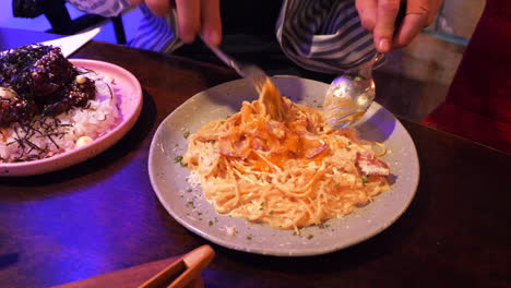 el hombre rompe la yema de huevo en un plato de espagueti carbonara y mezcla