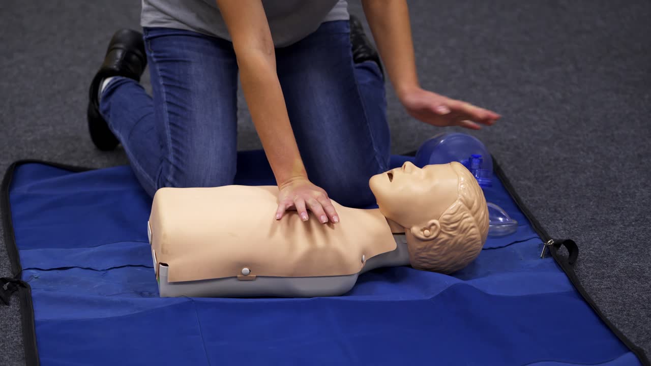Baby CPR dummy first aid training. Paramedic performing cardiopulmonary resuscitation on baby dummy with chest compression