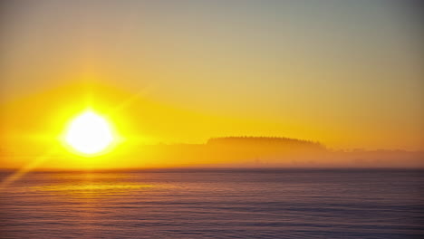 Timelapse-shot-of-beautiful-sunset-over-snow-covered-agricultural-fields-with-trees-in-the-background-during-evening-time