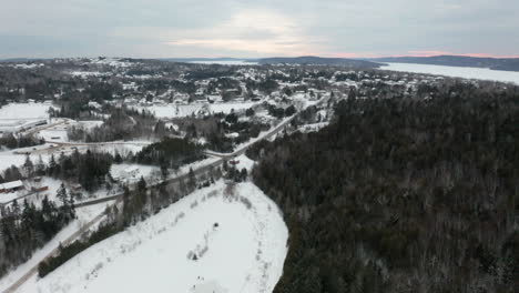 Aerial-flying-over-a-snowy-landscape-as-people-skate-on-a-frozen-pond-below