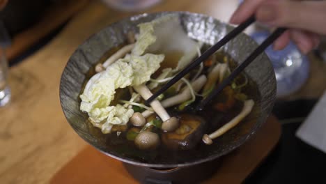 an aerial view of something is being cooked on a pan and someone is preparing the stuff with the help of chopstick