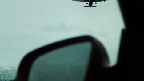 Sitting-in-a-car-and-plane-spotting-outside-the-airport---passenger-jet-flies-over-while-waiting