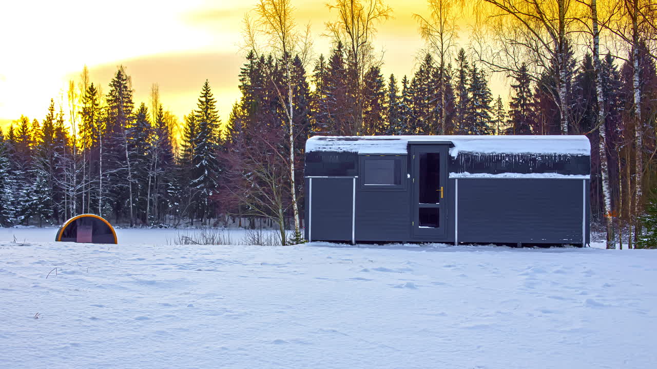 foto fija de una sauna de cabina y barril cubierta de nieve con un cielo espectacular