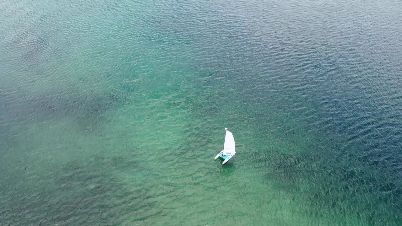 una vista aérea de un pequeño velero en el azul de las aguas caribeñas en un día soleado