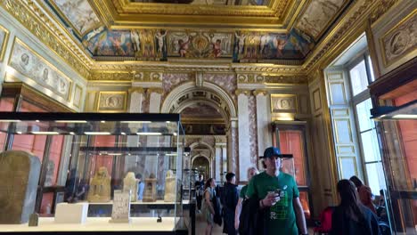 people viewing artifacts in ornate museum gallery