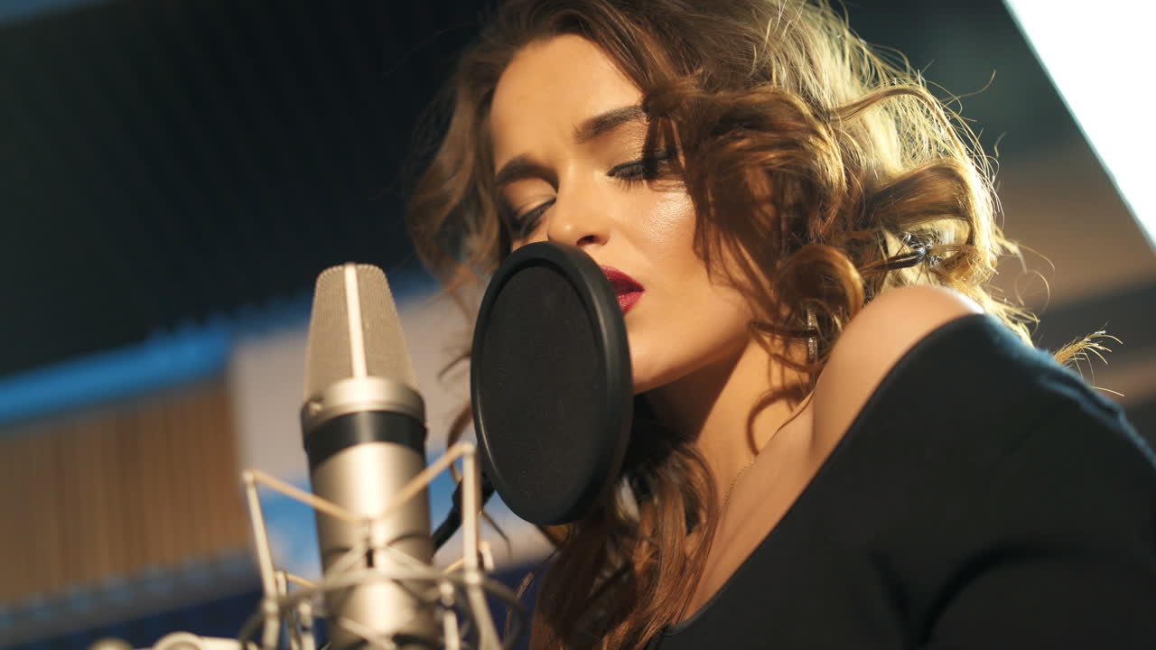 Beautiful young singer who recorded a song in a professional recording studio. Female singer