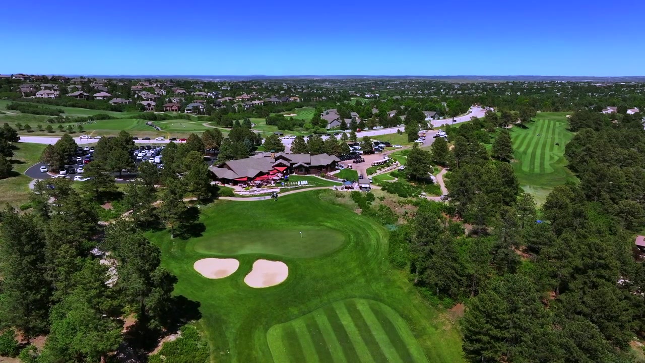 Club House del campo da golf The Ridge North Castle Pines Village, ripresa aerea con drone, Colorado. Golf estivo e primaverile con vista sulle Montagne Rocciose del Front Range. Golf cart, fairway, bunker di sabbia, mattina soleggiata, cielo blu, movimento in avanti.
