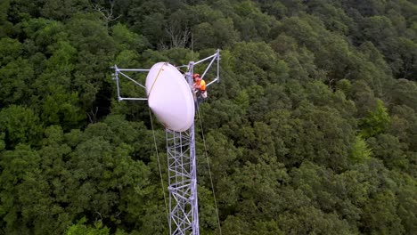 workers install communications dish on tower aerial near in sampson nc, north carolina