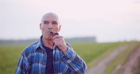 granjero calvo contento fumando su pipa en el campo