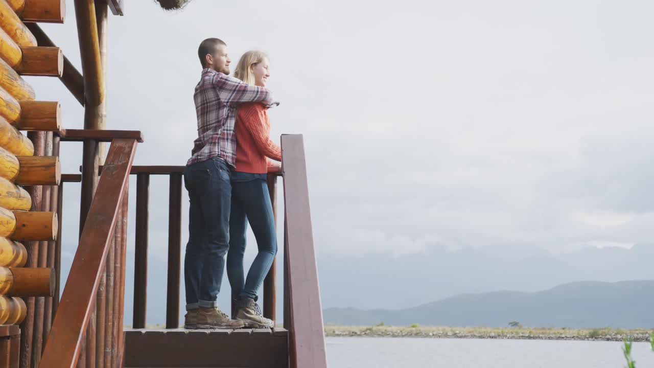 백인 커플이 집에서 함께 시간을 보내고, 포옹하고 전경을 바라보고 있습니다.