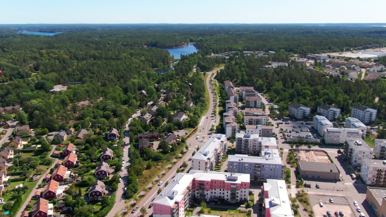 Широкая панорамная съемка жилых домов, расположенных в зеленом лесу с видом на отдаленное озеро в Густавсберге. Отлично подходит для стоковых видеоматериалов о городской среде, интегрированной в природу.
