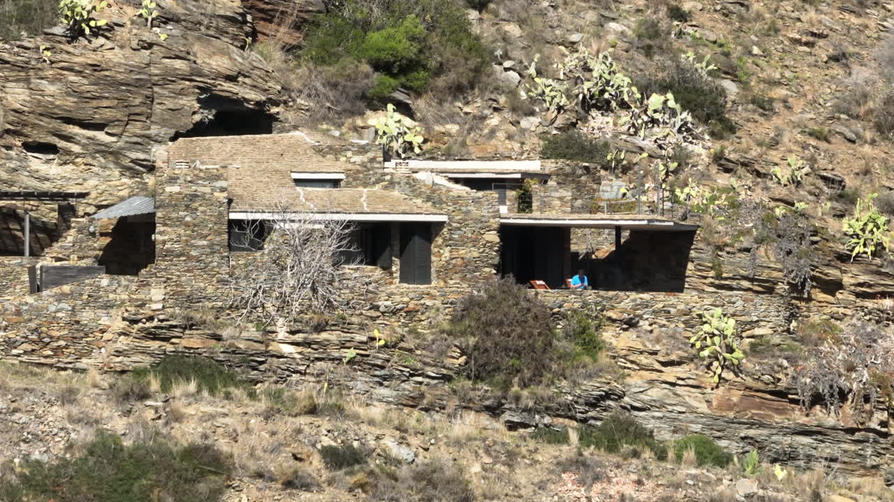 vista aérea orbitando impresionante casa de piedra construida en los acantilados del parque nacional cap de creus rocosa ladera de la montaña