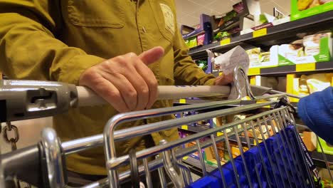 a man briskly pushing a shopping cart in a hurry, tapping his thumb. close up.