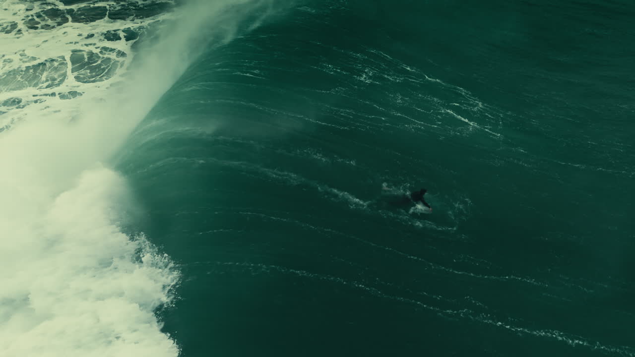 Vista aerea di un surfista che cavalca un'onda oceanica gigantesca vicino a una costa rocciosa