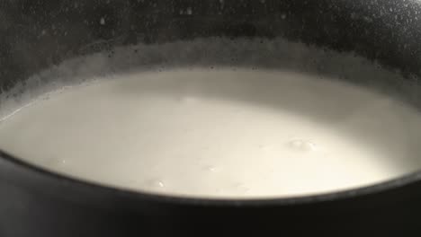 Milch-In-Einem-Schwarzen-Topf-Erhitzen,-Bis-Blasen-Entstehen