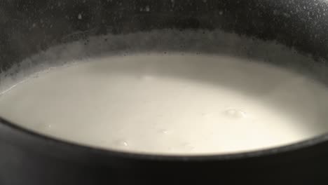 heating milk in a black pot until it bubbles